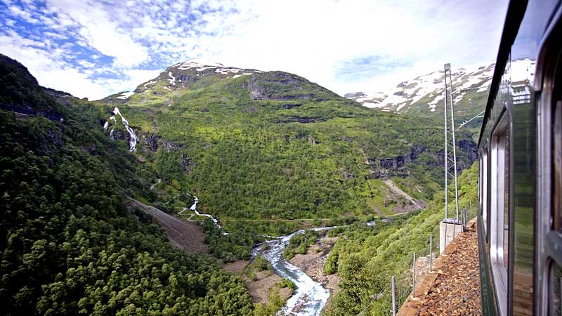Flåmbanan passerar frodiga dalar och mäktiga vattenfall i Norges fjällandskap.