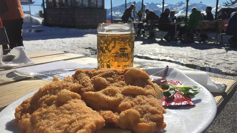 Att äta schnitzel och en kall öl smakar allra bäst i backen under en härlig skidresa i Saalbach Leogang